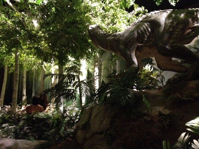 Adam and Eve overlooked by a dinosaur in the garden of eden.